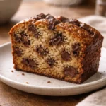 Slice of chocolate chip banana bread on a plate in a cozy home kitchen with natural light