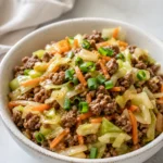 Egg roll in a bowl with ground beef, cabbage, carrots, and green onions.