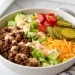 Low carb burger bowl with ground beef, lettuce, cheddar, pickles, tomatoes, and special sauce.