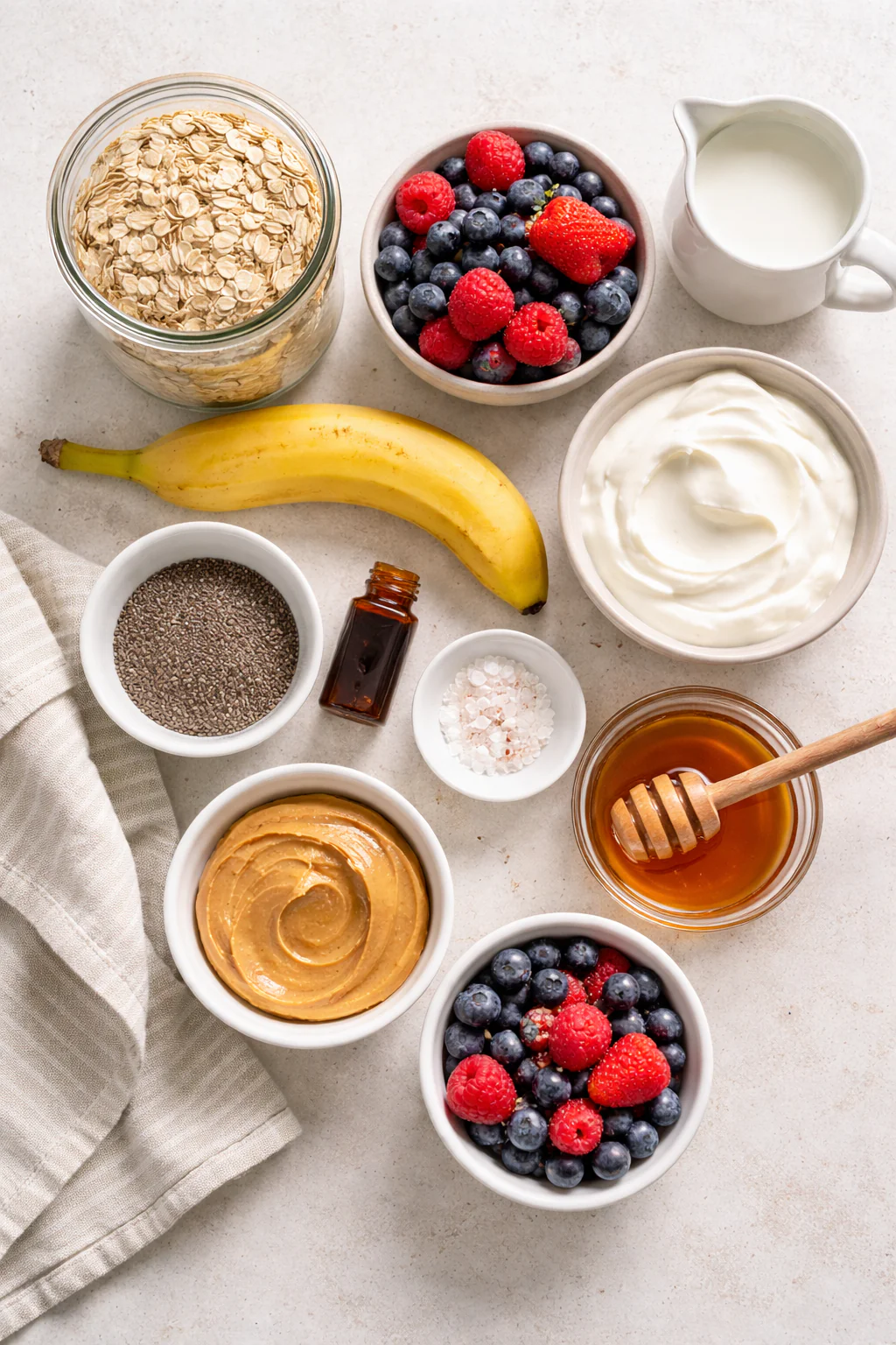 Bowls of oats, yogurt, milk, banana, and small bowls of chia and honey