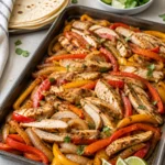 Sheet pan chicken fajitas with peppers, onions, lime, and tortillas.