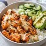 Air fryer salmon bites rice bowl with rice, cucumber, avocado, and creamy sauce.